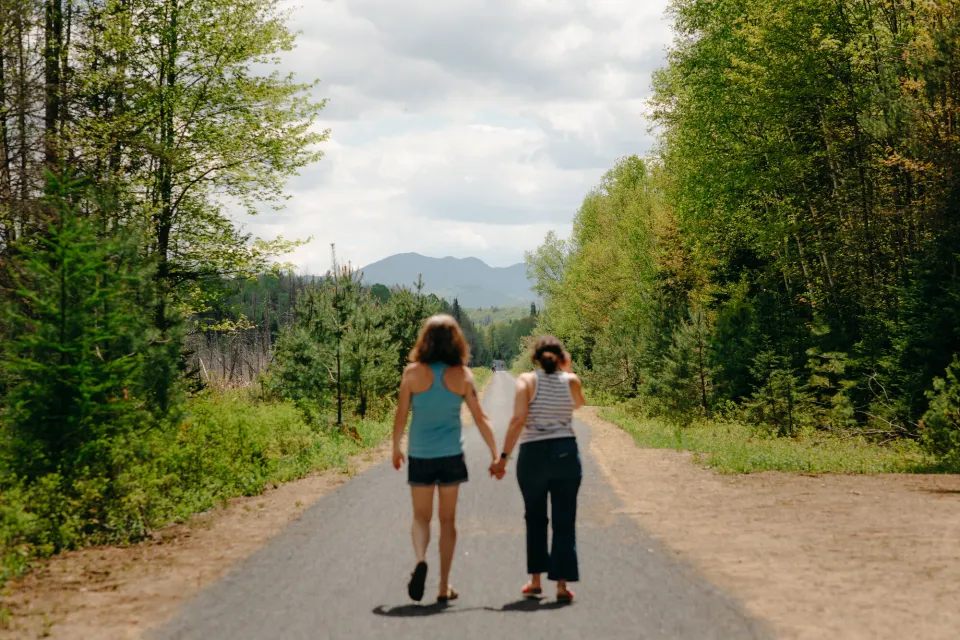 Two women walk on a nature trail in the woods.
