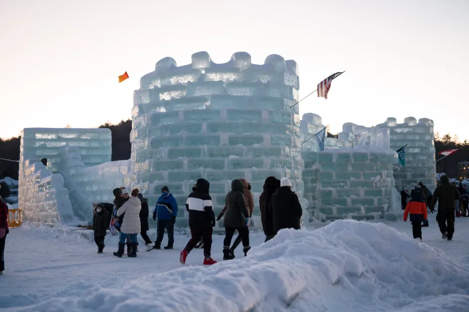 People walk around an ice castle in winter.